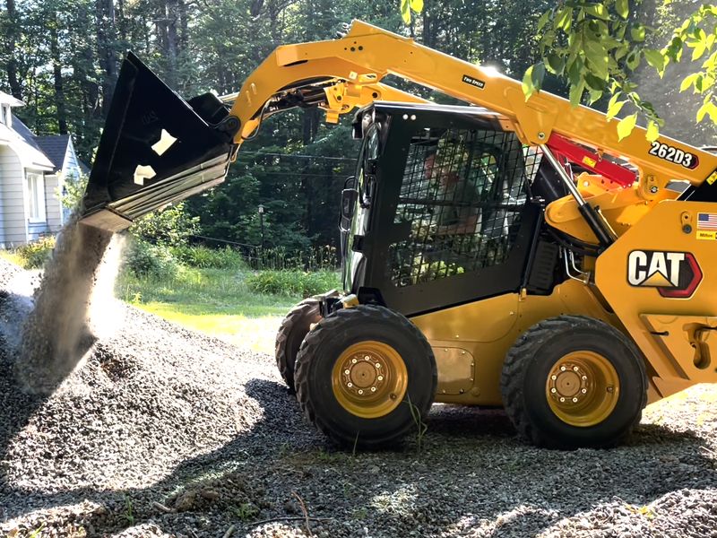 CAT 262D3 skid steer dumping a bucket of gravel